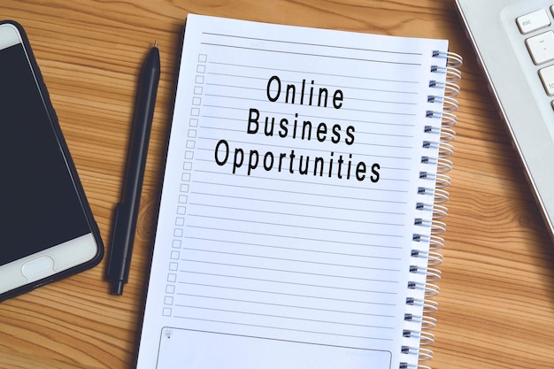 Online business opportunities label on notepad with laptop and smartphone on wooden table. Business concept