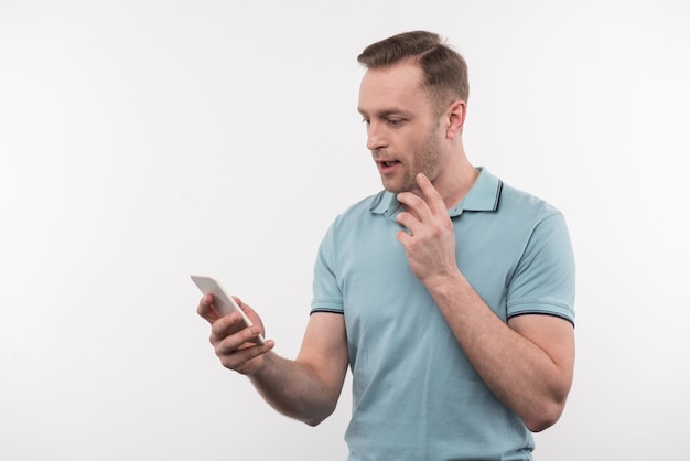 Online communication. Nice pleasant man holding his phone while checking messages