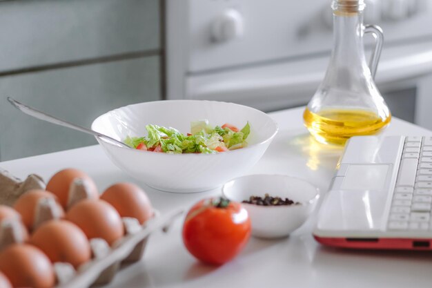 Online cooking Preparing salad using digital cookbook Fresh vegetables and laptop in home kitchen