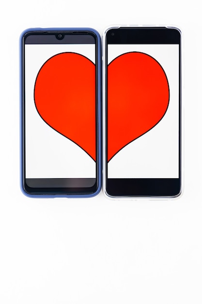 Online dating concept. Halves of the heart on the two smartphones screens. Valentine's Day concept