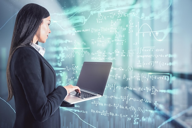 Online education concept with businesswoman with laptop in front of virtual wall with mathematical formulas