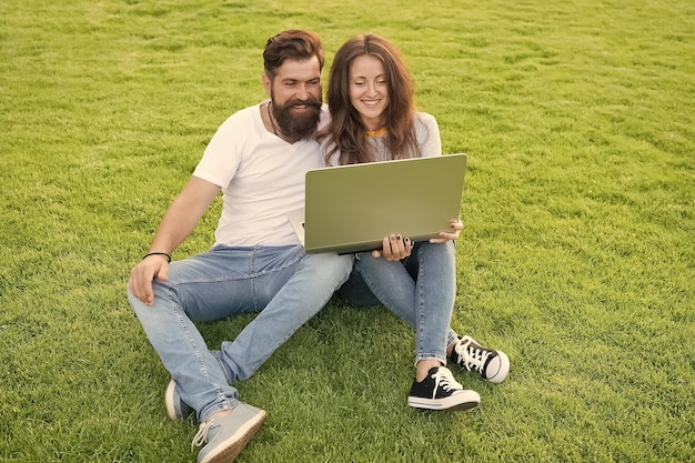 Online entertainment platform Subscribe online streaming services Modern technologies Couple sit lawn with notebook Surfing internet Spend leisure computer Man girl looking screen Online life