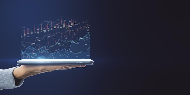 Online investing concept with virtual financial chart quotes and graphs above digital tablet on man hand with blank dark backdrop Mock up