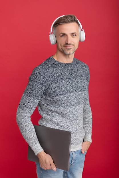 Online learning when it suits you. Happy guy in headphones hold laptop. Listening to audio courses online. Educational podcasts for adults. E-learning.