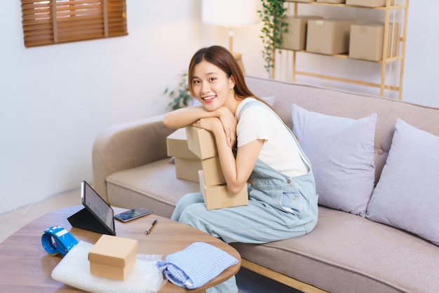 Online merchant concept Female entrepreneur holds parcel boxes and smiling while looking at camera