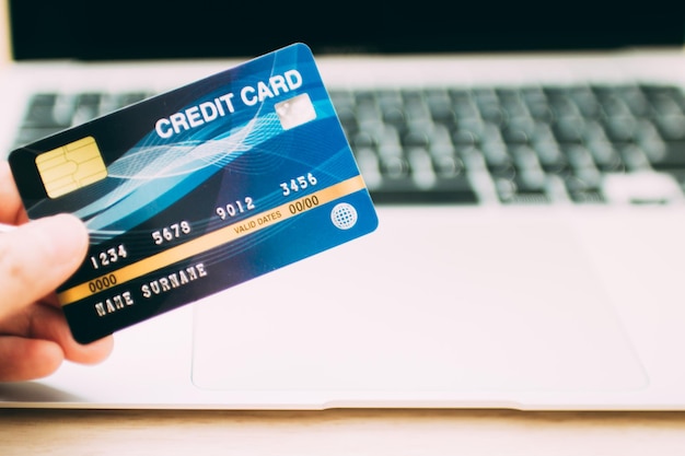 Online payment concept. Hand holding a credit card and using laptop for online shopping.