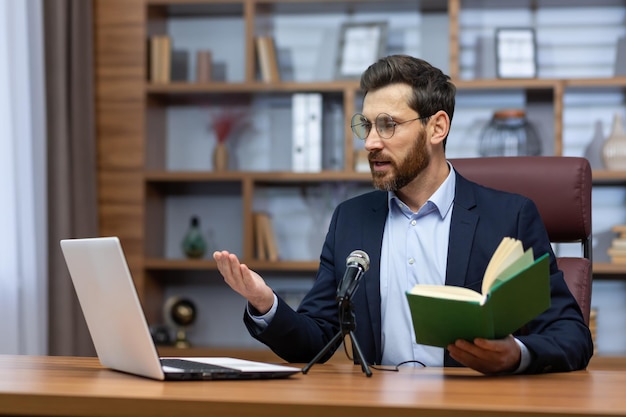 Online presentation of the book a young man writer author in a suit sits in the office at a table in