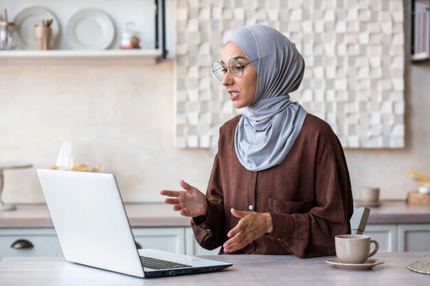 Online psychotherapy session a young female muslim psychologist in a hijab sits at home in front of