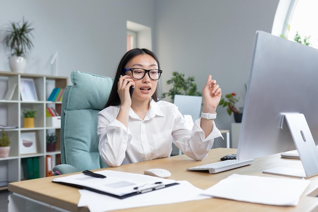 Online sales a young beautiful asian woman sales manager sells goods on the phone calls customers