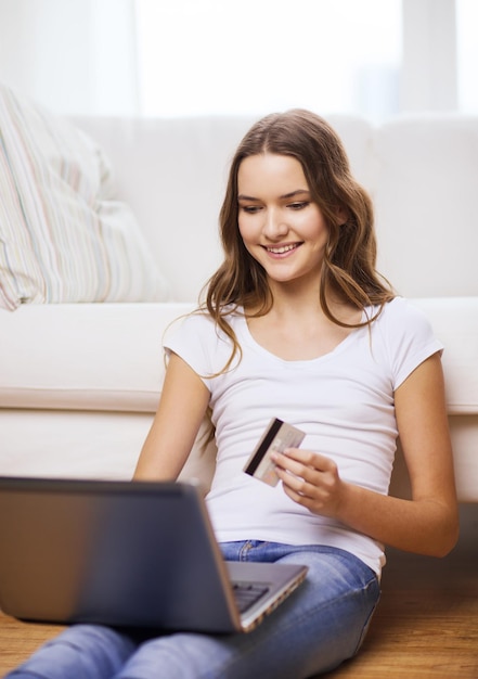 online shopping, banking and technology concept - smiling teenage girl with laptop computer and credit card at home