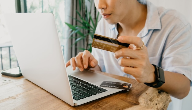 Online Shopping Concept Asian men are using credit cards to enter codes to shop using laptop computer.