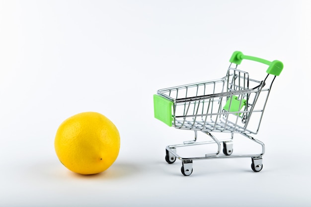 Online shopping concept. Cart and lemons on white