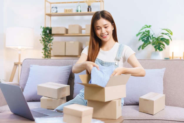 Online shopping concept Female entrepreneur packing product into parcel box to prepare send client