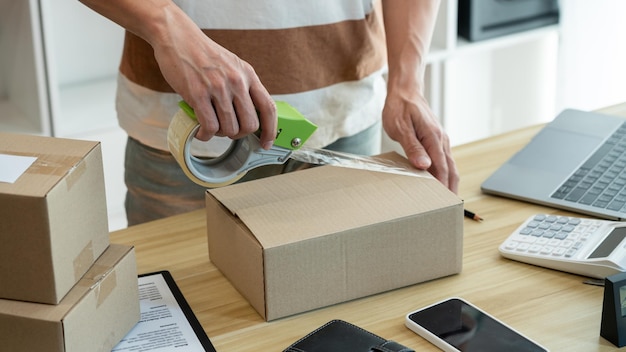 Photo online shopping concept the shop seller sealing the parcel of his goods on the desk