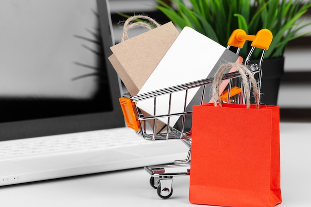 Online shopping concept. Shopping cart, laptop on the desk