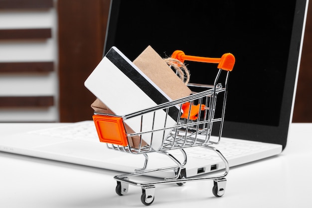 Online shopping concept. Shopping cart, laptop on the desk