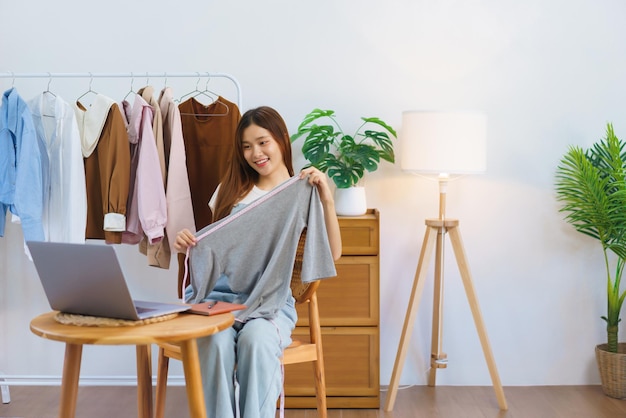 Online shopping concept Young Asian women is selling and present clothes detail on video streaming