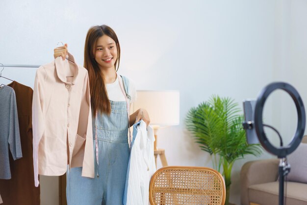 Online shopping concept Young Asian women is selling and presents shirt detail in streaming video