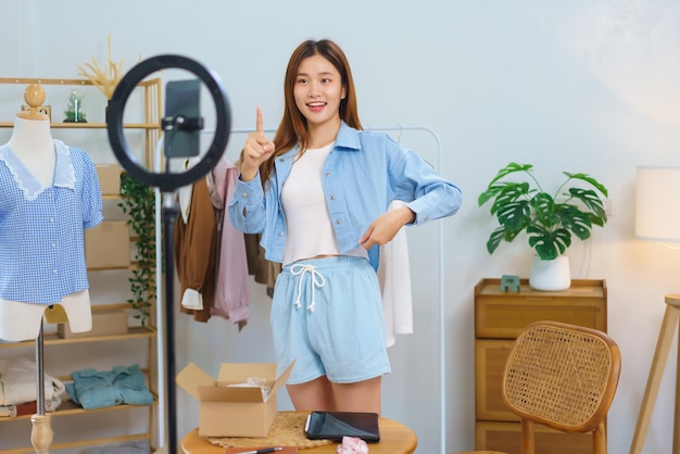 Online shopping concept Young Asian women trying on shirt and recommend clothes in streaming video