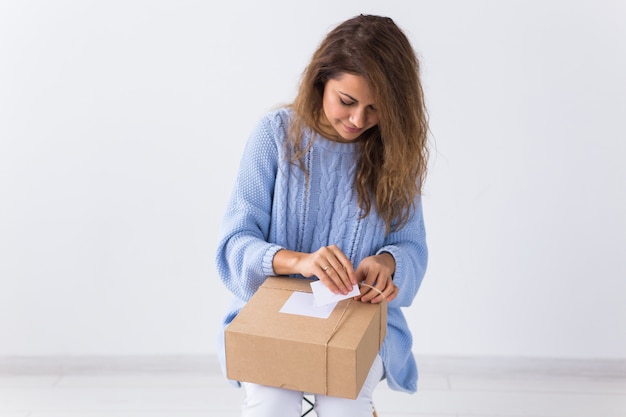 Online shopping, delivery and fashion concept - Woman sitting at home opening online clothing purchase