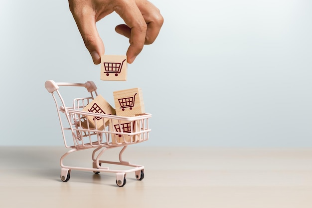 Online shopping delivery market concept hand holding wooden cubes block with shopping cart icons in shopping trolley sell marketing purchase delivery