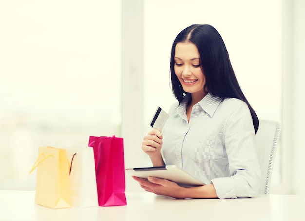 online shopping, electronics and gadget concept - smiling woman with blank screen tablet pc and shopping bags