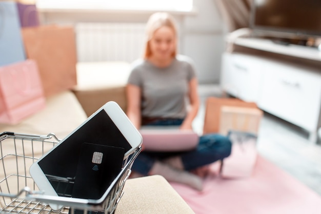 Online shopping at home. Black credit card and smartphone are ready for black Fridays sale on a background of a shopper with laptop