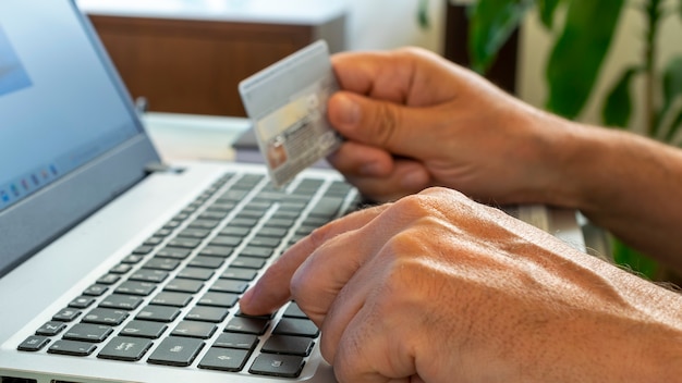 Online shopping. Man hand holding credit card and using laptop at office. home shopping concept