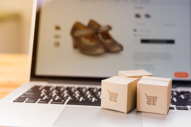 Online shopping - Paper cartons or parcel with a shopping cart logo on a laptop keyboard which web store shop on screen, Shopping service on The online web and offers home delivery.