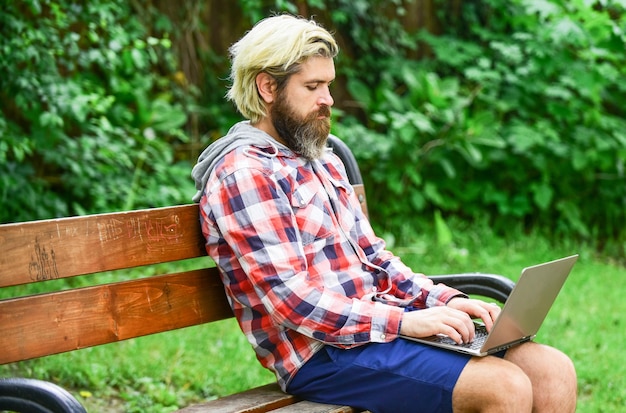 Online shopping Working online Hipster inspired work in park Fresh air Mobile internet You can work anywhere Agile business Bearded guy sit on bench in park nature background Work and relax