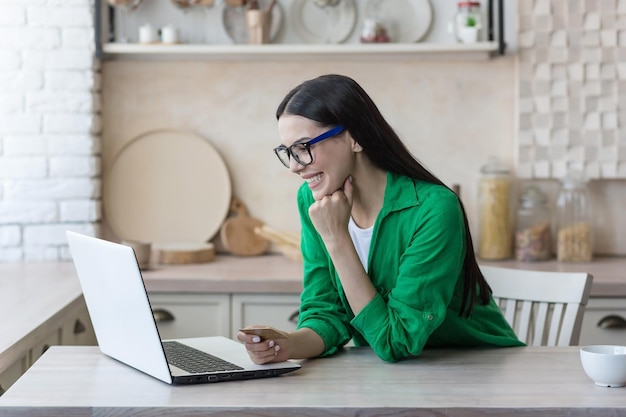 Online shopping a young beautiful woman in glasses and a green shirt sits at home with a laptop