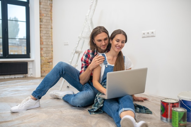 Online shopping. Young couple sitting on the floor and searching for something online