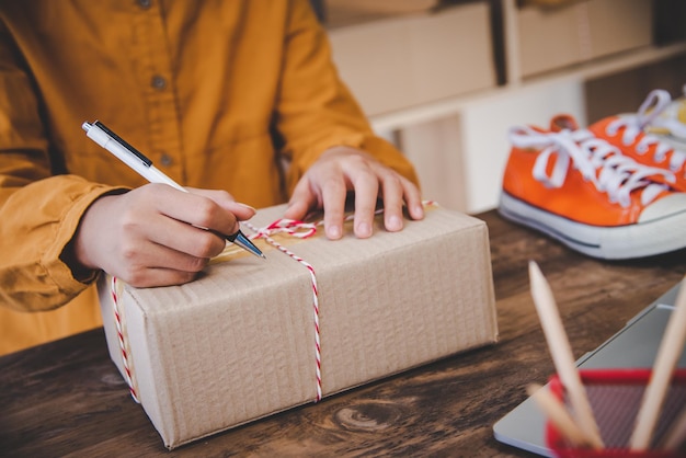 Online small business owner is writing the name, address on the product box to the customer according to the online order-Shopping online concept.