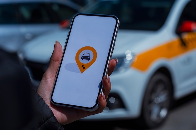 Online taxi in a smartphone. The girl holds the phone in her hands with a mobile application on the screen against the background of the car.