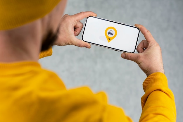 Online taxi on your phone. A man holds a smartphone with a white screen and a geolocation and location icon for a taxi.