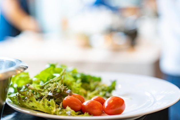 Only green vegetable and tomato on the white dish on the blur backtround decorate and prepare for the main ingredient meal