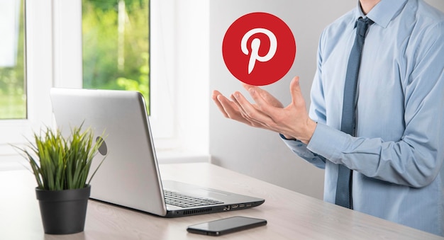 OnokUkraine July 142021Businessman holds clicks pinterest icon in his handsSocial networkglobal network and data customer connectioninternational network