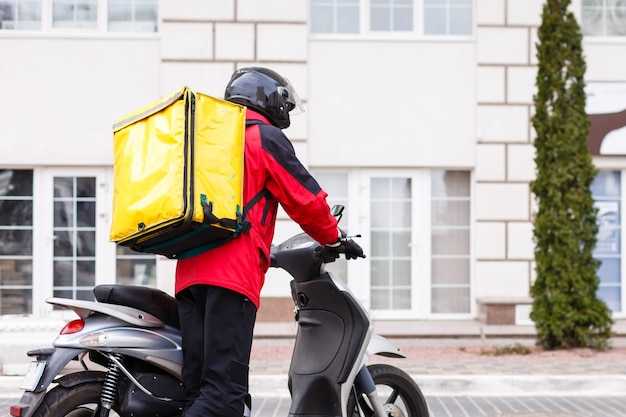 ?ontactless food delivery to customers home. Delivery service worker with thermal backpack quick delivering food at doorstep in quarantine from restaurant, supermarket or cafe . Online ordering food