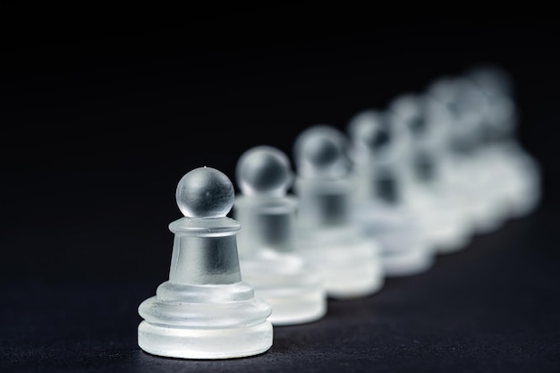 Opaque glass chess pawn row on black background selective focus closeup