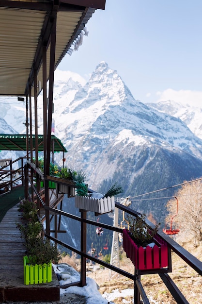 An open-air cafe high in the snow-capped mountains on a clear, sunny day. Winter sports and outdoor activities. Selective focus. Vertical.