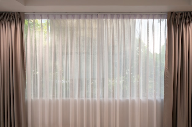 Open beige curtain with light filter fabric on window at home