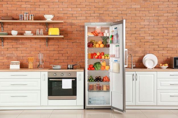 Open big fridge with products in interior of kitchen