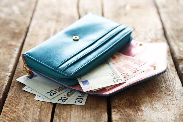 Open blue purse with euro banknotes on wooden table