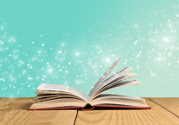 Open book, hardback books on wooden table.