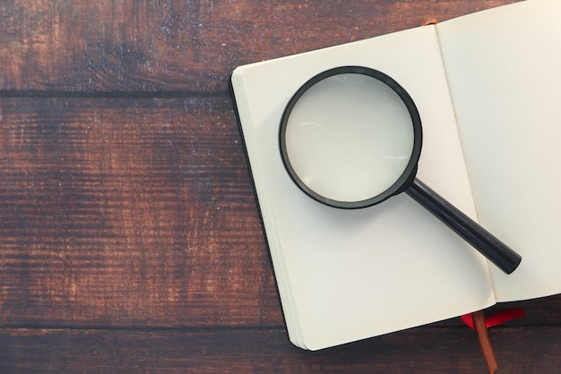 Open book and magnifying glass on table 