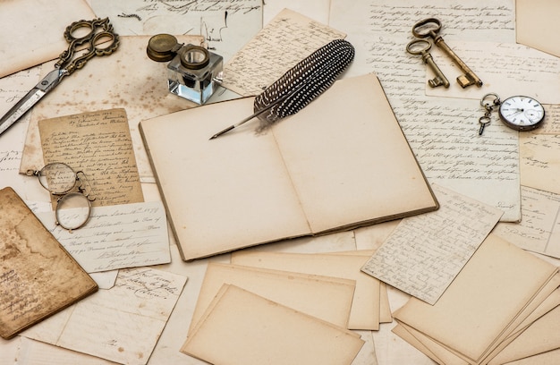 Open book, old letter and antique feather pen. Used paper background