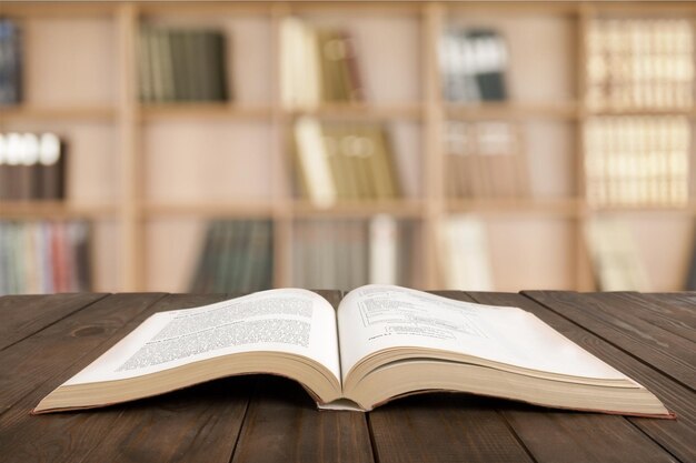 Open book on wood planks over sky with leaves background