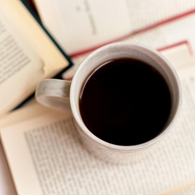 Open books and coffee mug on a book, top view. Student eating breakfast, study concept.