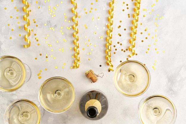 Open bottle of champagne and filled glasses of champagne on the festive table, New Year or Christmas celebration concept. Top view.