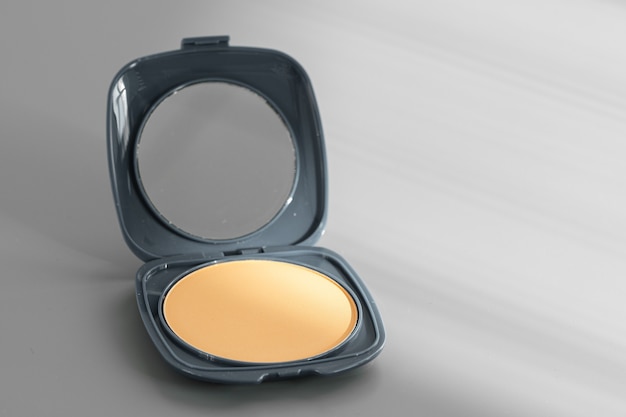 Open box with make up face powder on gray surface